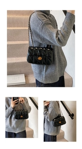 Détail du sac matelassé noir avec fermoir tournant doré et bandoulière chaîne en cuir