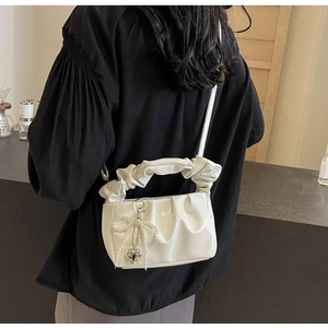 Detail of white ruched shoulder bag with pearl bow and silver heart pendant charm