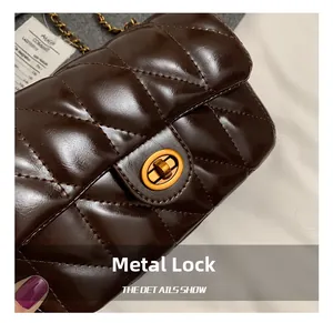Détail du fermoir tournant en métal doré sur un sac bandoulière matelassé couleur chocolat