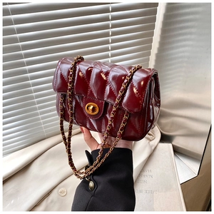 Détail d'un sac en cuir matelassé bordeaux avec fermoir doré et bandoulière chaîne