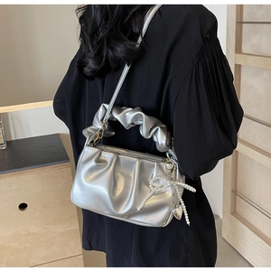 Detail of silver metallic pleated handbag with pearl bow charm and cloud-style handle