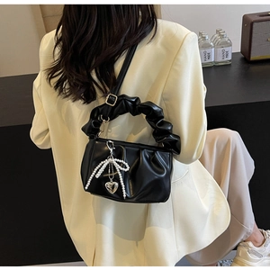 Detail of black pleated PU handbag featuring a pearl bow charm and ruffled handle