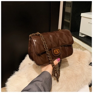 Gros plan d'un sac en cuir marron foncé matelassé avec chaîne dorée et fermoir pivotant