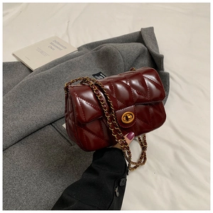 Détail du sac matelassé bordeaux en cuir verni avec chaîne dorée et fermoir rotatif