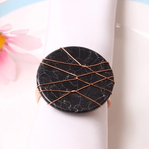 Detailed close-up of handmade black marble napkin ring with copper wire wrapping