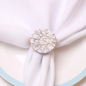 Macro detail of handmade marble napkin ring with gold wire wrap on white linen