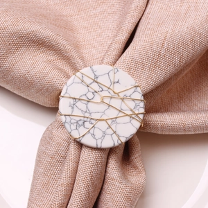 Detail of handmade marble napkin ring with gold wire wrapping on a linen napkin