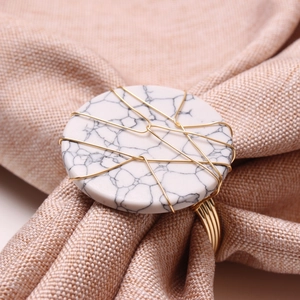 Detail of white marble napkin ring wrapped in golden wire on linen fabric