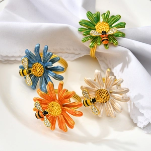 Détail de ronds de serviette marguerite et abeille colorés sur de la vaisselle blanche