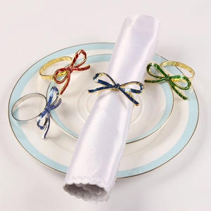Detail of colorful bow-shaped napkin rings on a white porcelain plate for wedding decor