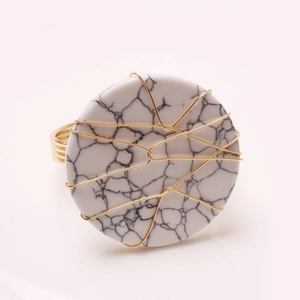 Macro detail of handmade napkin ring with white marble stone and gold wire wrapping