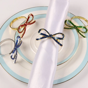 Detailed view of enamel bow napkin rings in assorted colors displayed on white plates