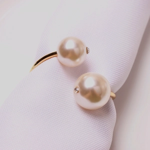 Elegant gold open ring featuring two white pearls and subtle zircon accents on a white background