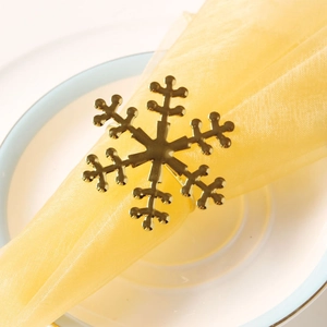 Macro shot of gold snowflake napkin ring on a beige gauze napkin and white porcelain plate