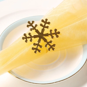 Detailed view of a gold snowflake napkin ring on a white plate with elegant napkin