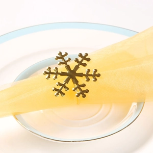 Close-up of a golden snowflake napkin ring set on a yellow napkin for festive table decor