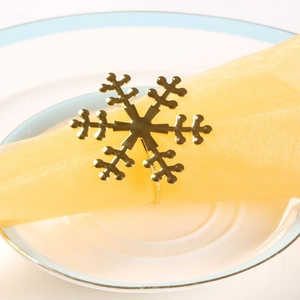 Macro detail of golden snowflake napkin ring with polished finish on a yellow napkin