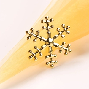 Elegant gold snowflake napkin ring on yellow fabric, perfect for Christmas table decor