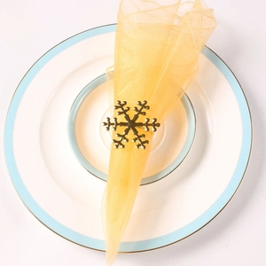 Golden snowflake napkin ring on a white ceramic plate for festive Christmas table decor