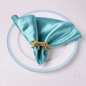 Gros plan d'un rond de serviette léopard doré sur satin bleu pour une table de luxe