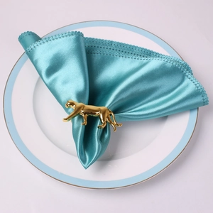 Rond de serviette léopard doré poli avec serviette en dentelle bleue sur assiette blanche