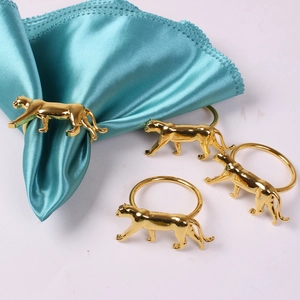 Vue détaillée des ronds de serviette léopard en métal doré sur satin bleu élégant