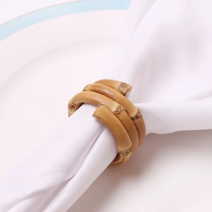 Rond de serviette en bambou naturel avec design en spirale sur une assiette blanche