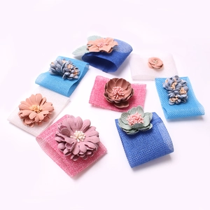 Détail de ronds de serviette fleurs en toile de jute bleus, roses et blancs avec pétales 3D