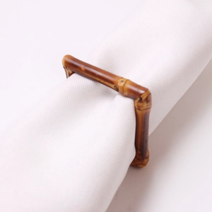 Détail d'un rond de serviette carré style bambou marron foncé sur tissu blanc