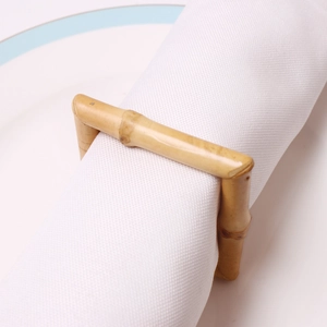Détail du rond de serviette carré en bambou avec texture boisée sur assiette blanche