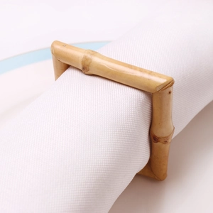 Détail d'un rond de serviette en bambou naturel avec texture bois sur serviette blanche