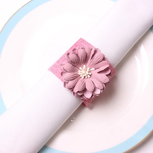 Rond de serviette fleur rose en toile de jute sur une assiette en céramique blanche