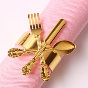 Golden napkin ring featuring a cutlery design with fork and spoon on pink napkin