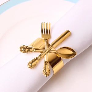 Close-up of golden metal napkin ring with miniature fork spoon and knife decor