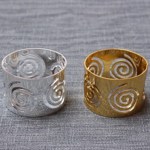 Detailed view of metal hollow swirl napkin rings in polished gold and silver finishes