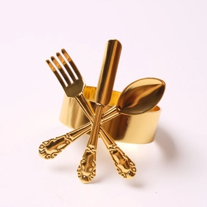 Detail of gold metal napkin ring with miniature crossed fork, knife and spoon design