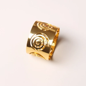 Detail of gold metal napkin ring featuring intricate hollow spiral swirl patterns
