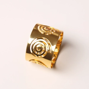 Macro view of golden metal napkin ring with hollow spiral design on a plain background