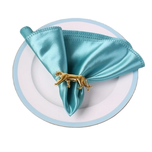 Rond de serviette léopard en métal doré sur une serviette bleu clair sur une assiette blanche