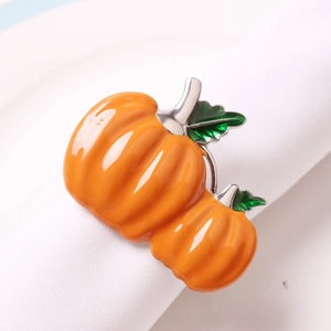Polished double pumpkin napkin ring with orange enamel and green leaves on white napkin
