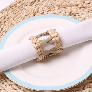 Detail of hand-woven natural bamboo napkin ring on a white linen napkin and ceramic plate