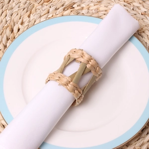 Close-up of handmade woven straw napkin ring with natural bamboo stem on a white cloth