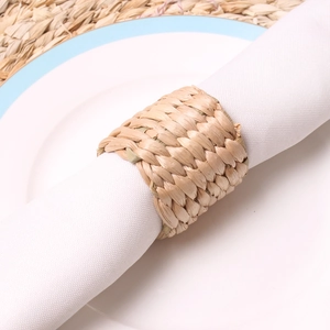 Natural hand-woven water hyacinth napkin ring on white linen with a ceramic plate