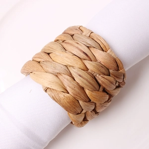 Close-up of handmade woven napkin ring featuring natural seagrass texture on white fabric