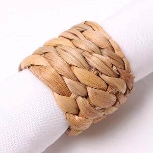 Close-up of handwoven natural grass napkin rings on white cloth napkins for table decor