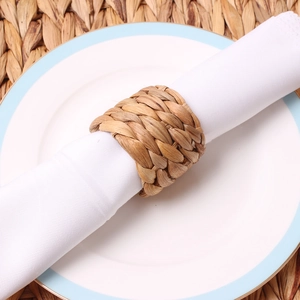 Detailed close-up of handmade woven napkin ring made from natural seagrass on white cloth