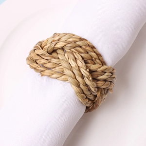 Detail of a handmade natural woven grass napkin ring on a white cloth napkin and plate