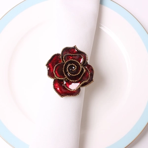 Close-up of elegant red rose napkin ring with gold beaded edges on a white cloth