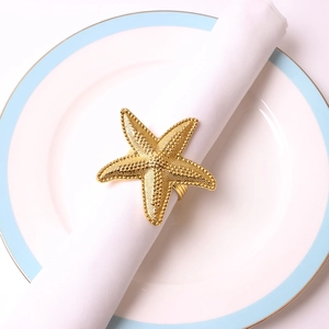 Elegant gold starfish napkin ring on white fabric napkin in a luxury table setting