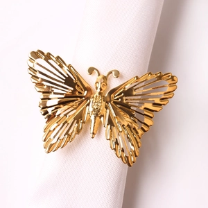 Detailed view of a gold hollow butterfly napkin ring on a white rolled napkin